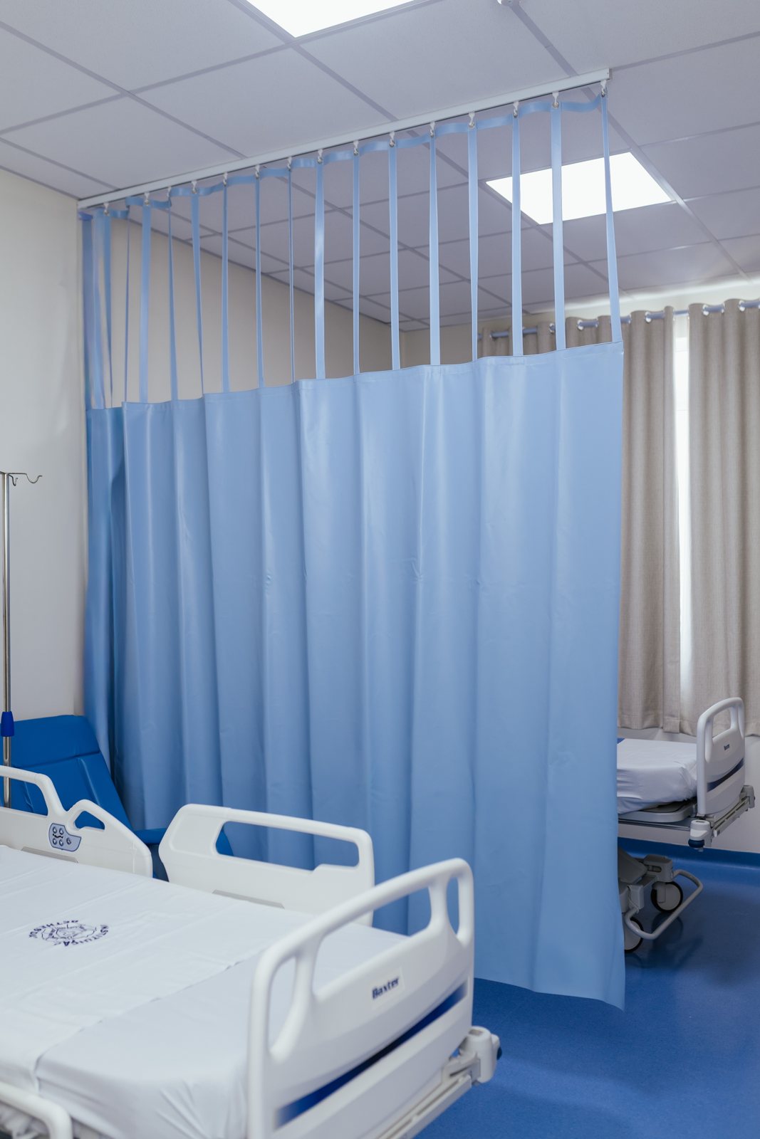 Cortina hospitalar azul com tela debrum instalada em enfermaria