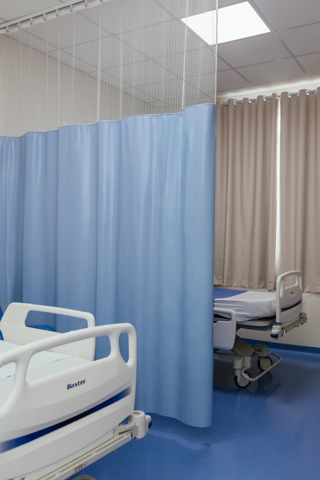 Cortina hospitalar azul separando leitos em quarto de internação